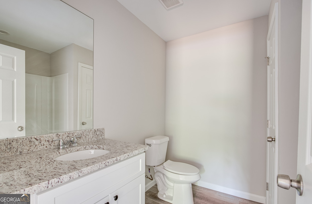 54 Lyla Lane Canon, GA 30520 - Photo 16 of 18 a bathroom with a granite countertop sink a toilet and a mirror