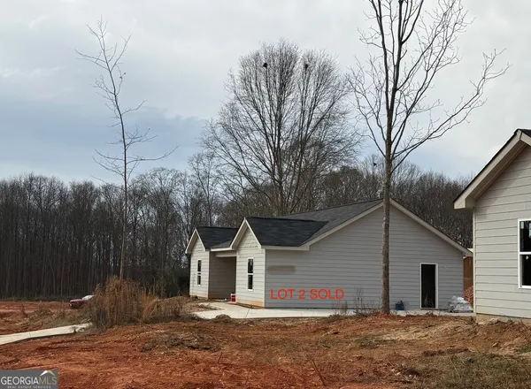 a view of a house with a small yard and large tree