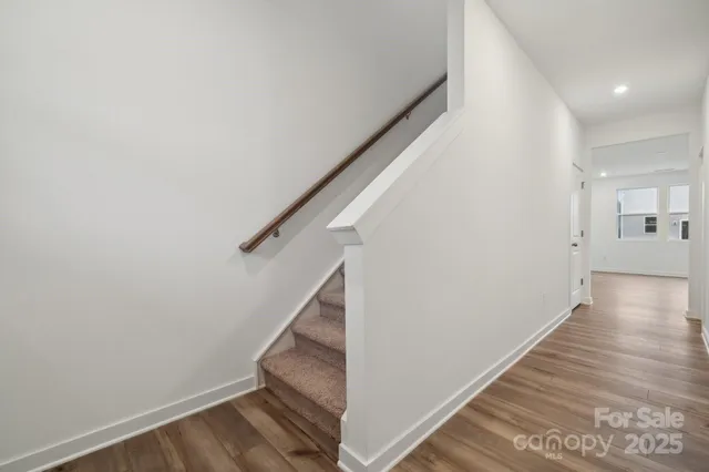 a view of a hallway with wooden floor and staircase