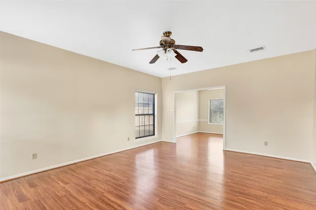 a view of empty room with wooden floor and ceiling fan