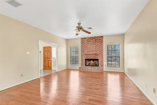 wooden floor fireplace and windows in an empty room