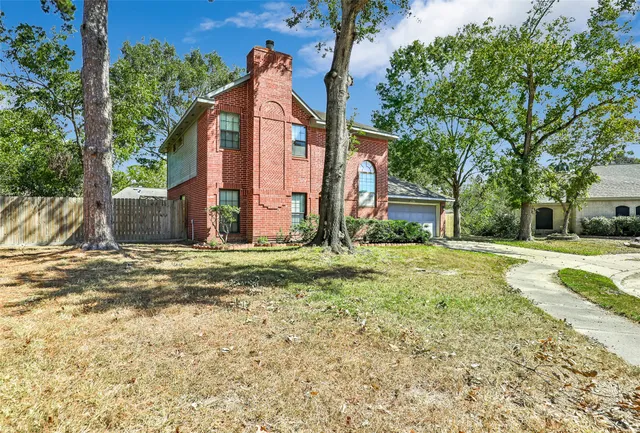 a view of a house with a yard and large tree