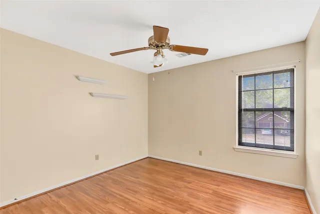 a view of an empty room with wooden floor and windows
