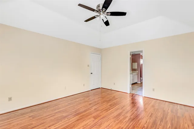 an empty room with wooden floor and a ceiling fan