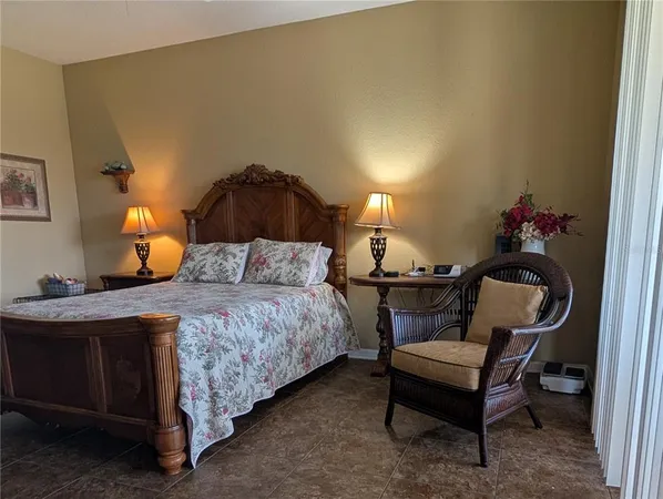 a bedroom with a bed a lamp and a potted plant