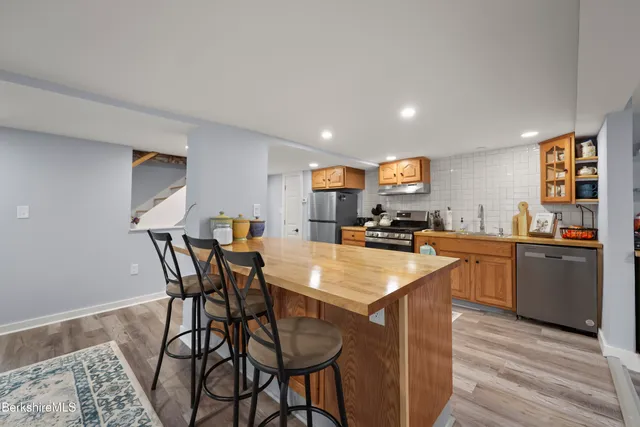 a kitchen with kitchen island granite countertop wooden floor and stainless steel appliances