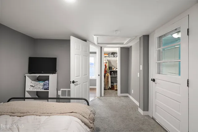 a bedroom with a bed and a flat tv screen on wall