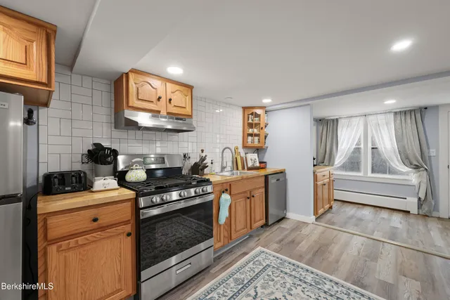 a kitchen with stainless steel appliances granite countertop a stove a sink and a microwave