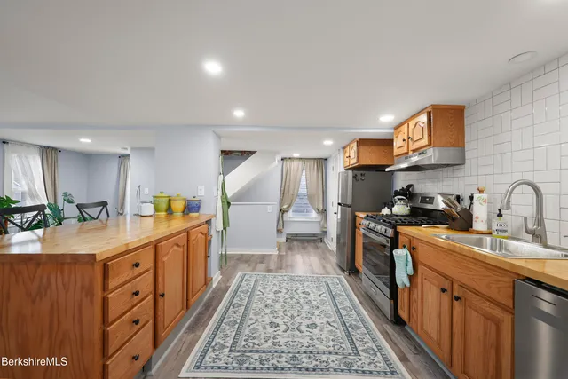 a large kitchen with stainless steel appliances granite countertop a lot of counter space and wooden floors