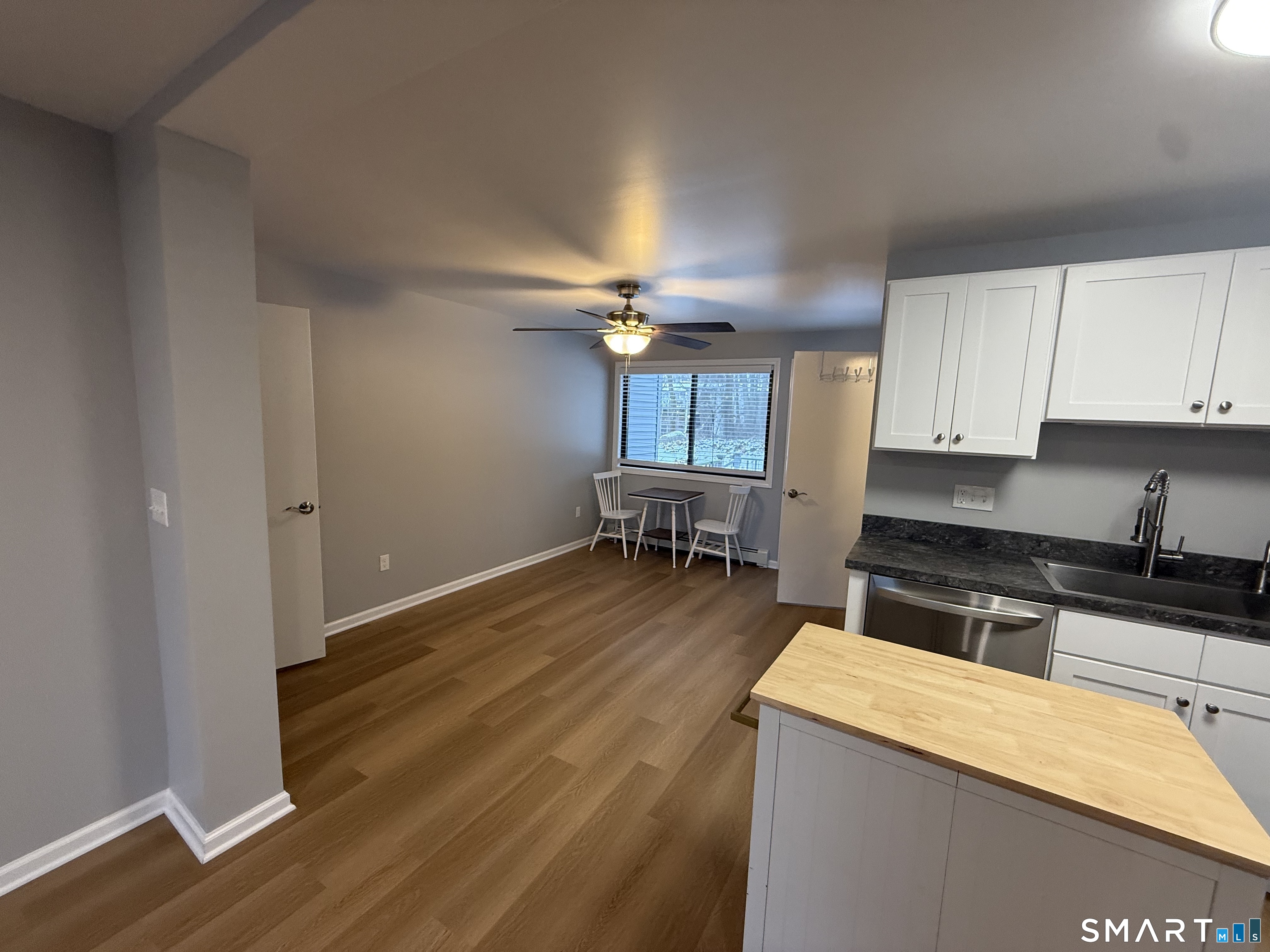 292 Meridian Street, Unit K Groton, CT 06340 - Photo 5 of 20 a kitchen with granite countertop a stove a sink and white cabinets with wooden floor