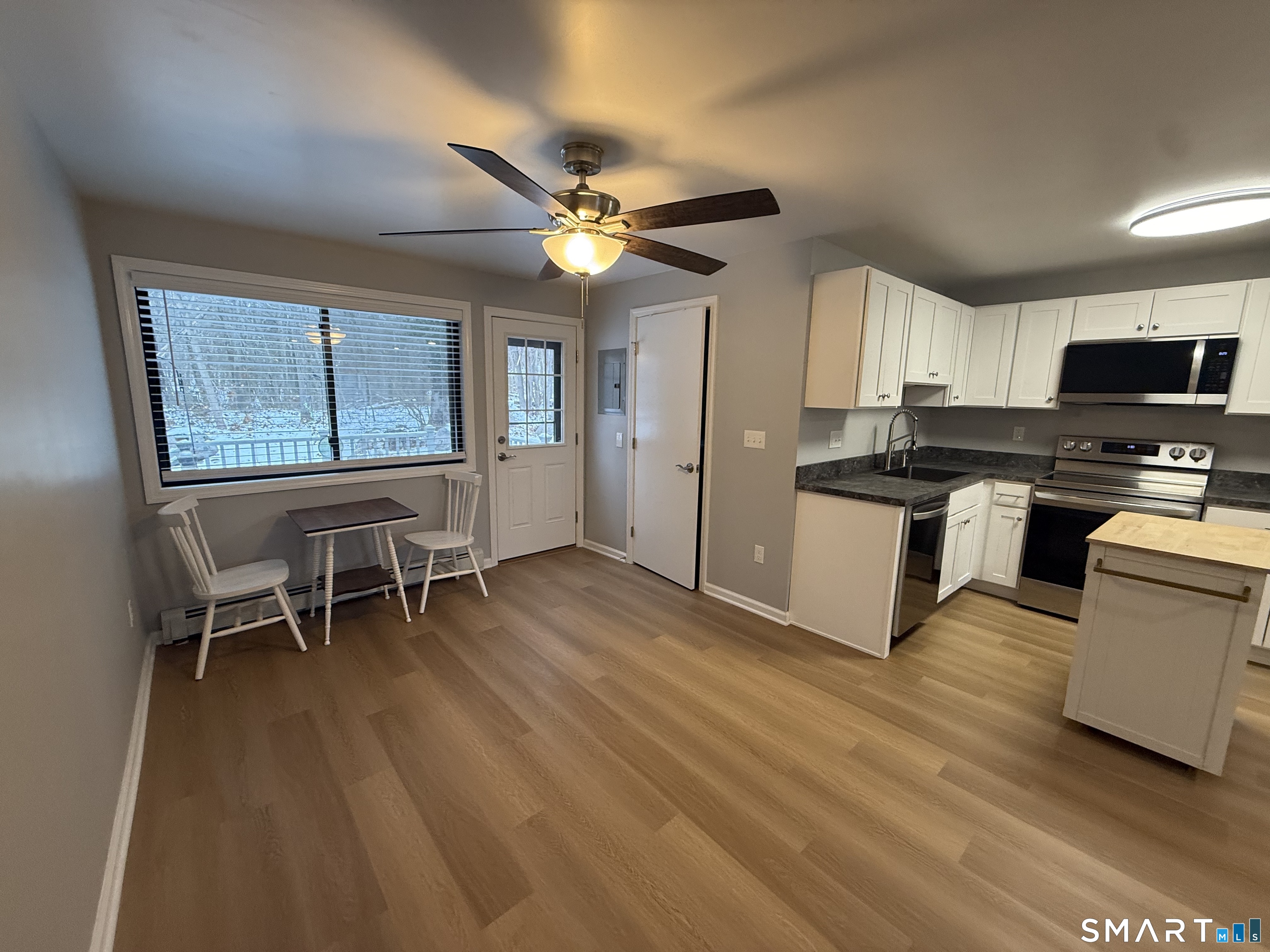 292 Meridian Street, Unit K Groton, CT 06340 - Photo 7 of 20 a kitchen with stainless steel appliances granite countertop a stove top oven a sink a dining table and chairs with wooden floor