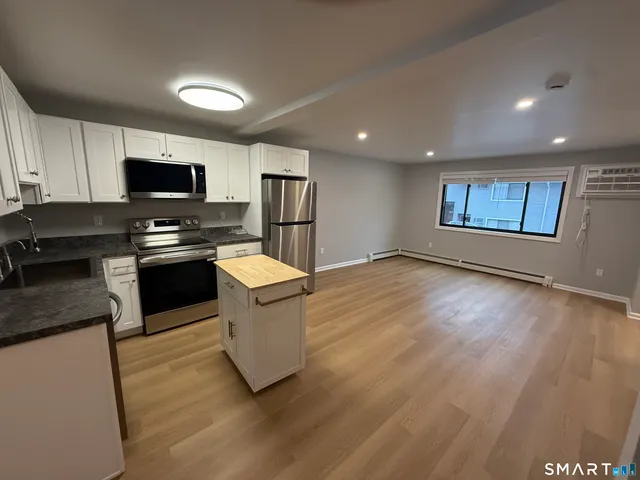 a kitchen with stainless steel appliances granite countertop a stove a sink and a refrigerator