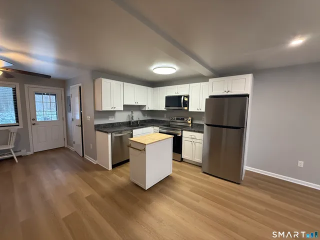 a kitchen with granite countertop a refrigerator and a stove top oven