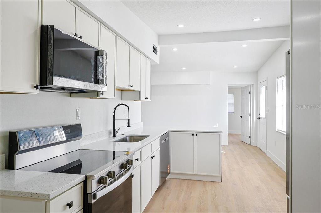 4061 Ferrow Street Orlando, FL 32811 - Photo 11 of 31 a kitchen with stainless steel appliances a stove microwave and sink