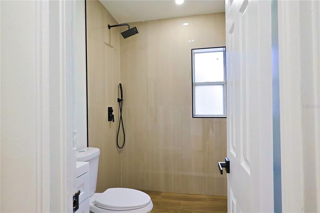 4061 Ferrow Street Orlando, FL 32811 - Photo 17 of 31 a bathroom with a granite countertop toilet and a shower