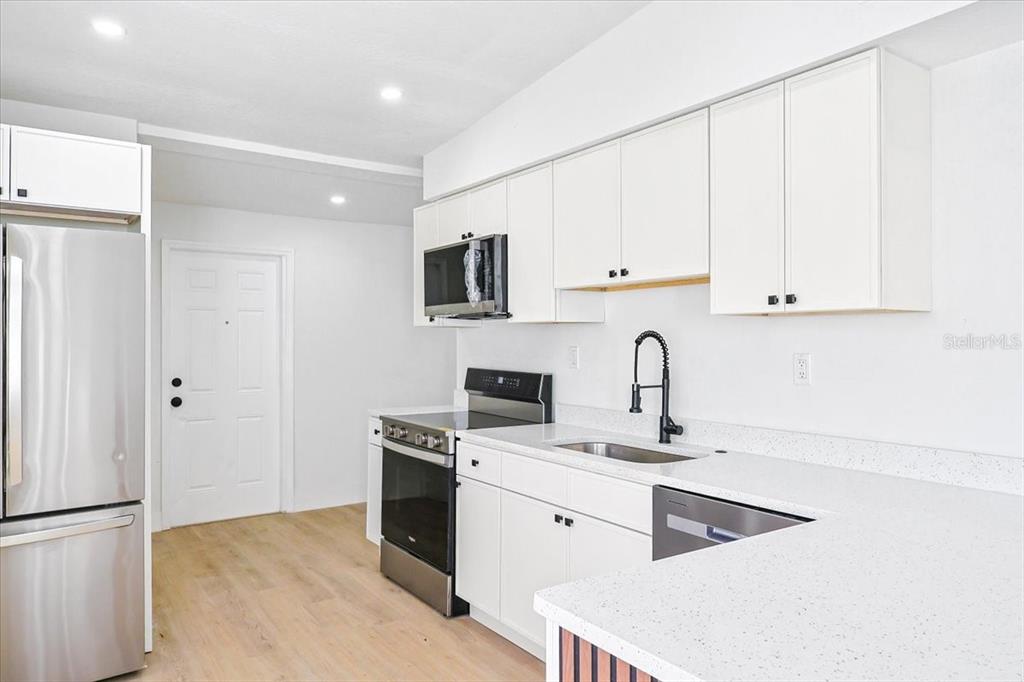 4061 Ferrow Street Orlando, FL 32811 - Photo 10 of 31 a kitchen with white cabinets sink and stainless steel appliances