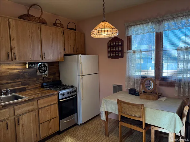 a kitchen with stainless steel appliances granite countertop a stove a refrigerator a dining table and chairs with wooden floor