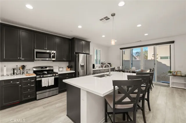 a kitchen with stainless steel appliances granite countertop a stove top oven a sink a stove a dining table and chairs