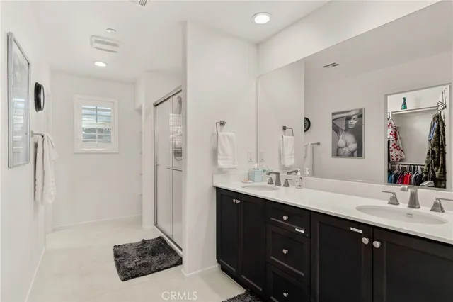 a bathroom with a sink double vanity granite tub shower and a mirror