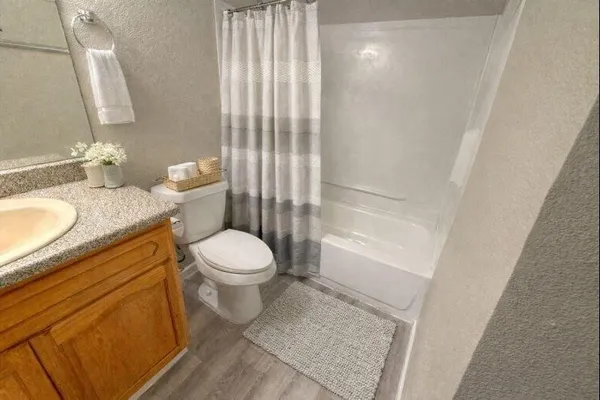 a bathroom with a granite countertop sink toilet a mirror and shower