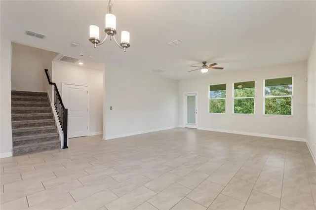 an empty room with windows and ceiling fan