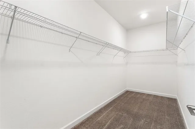 an empty room with chandelier fan and windows