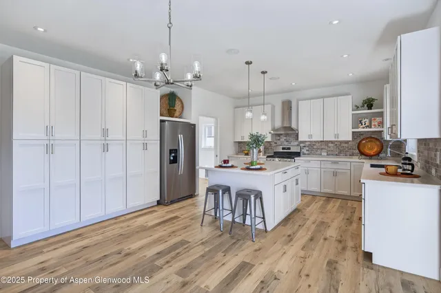 a kitchen with stainless steel appliances granite countertop a refrigerator a oven a white stove a sink dishwasher and white cabinets with wooden floor