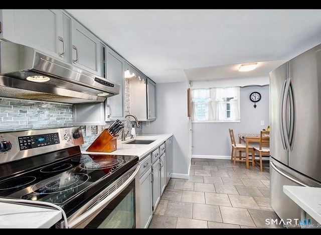 437 Hulls Farm Road Fairfield, CT 06890 - Photo 4 of 15 a kitchen with stainless steel appliances granite countertop a stove a sink and a refrigerator