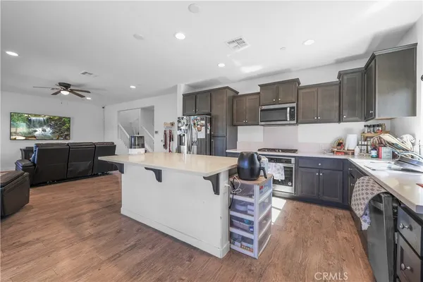 a large white kitchen with stainless steel appliances kitchen island granite countertop a large counter top and a stove