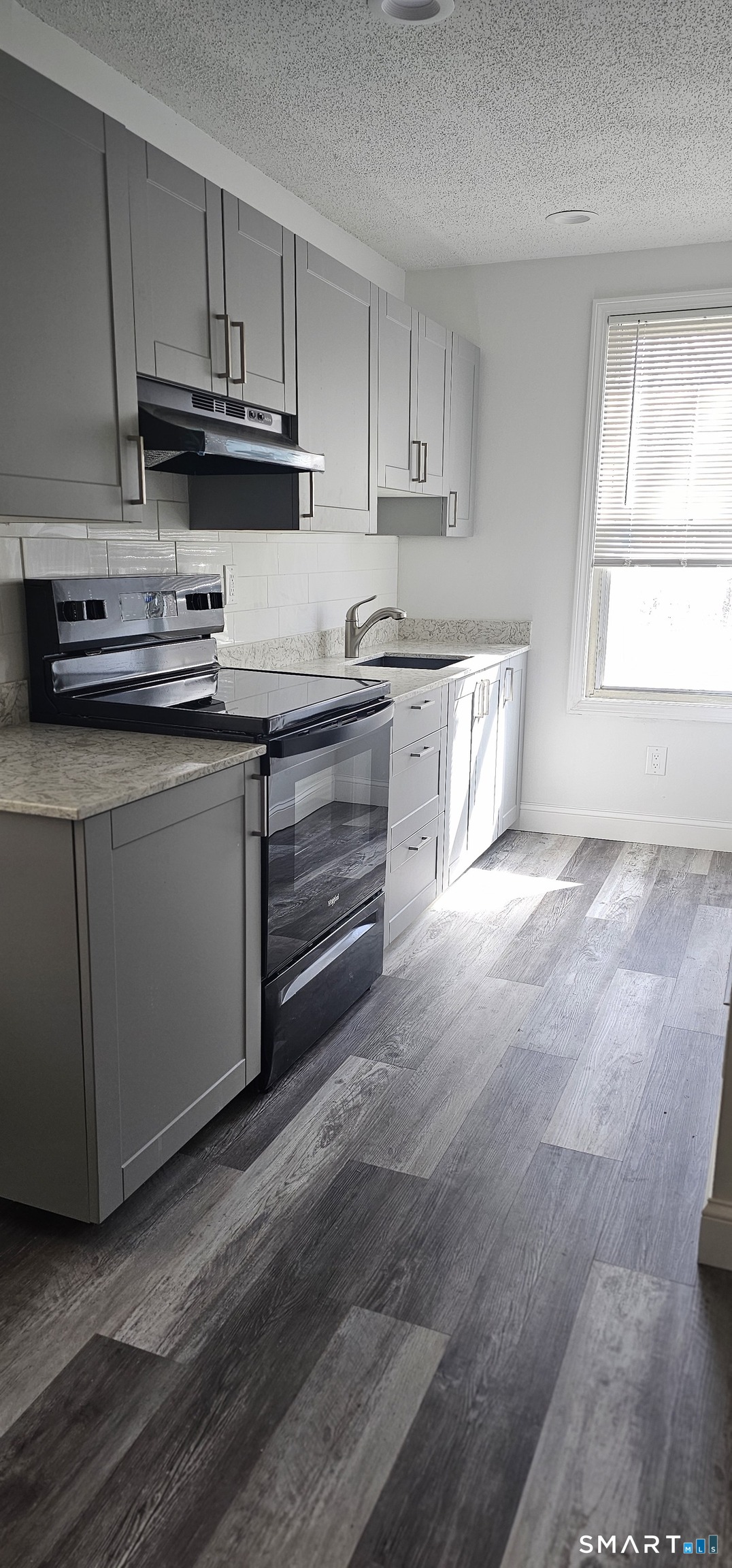 a kitchen with kitchen island granite countertop a sink cabinets and a window