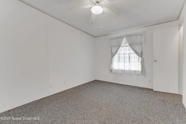 an empty room with windows and chandelier fan