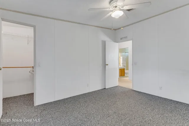 an empty room with closet and a ceiling fan