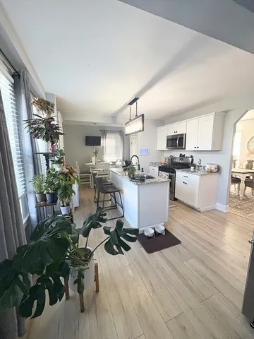 a living room with stainless steel appliances kitchen island granite countertop furniture a rug kitchen view and a window