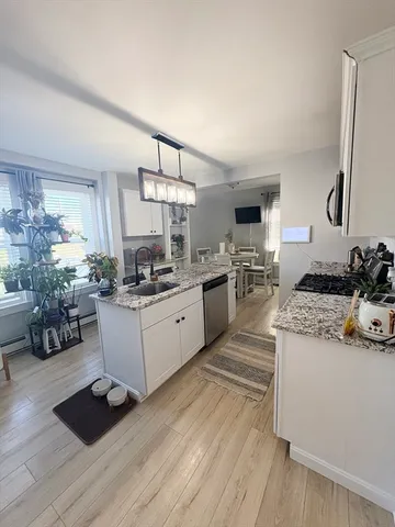 a kitchen with granite countertop a stove a sink dishwasher and a refrigerator with wooden floor