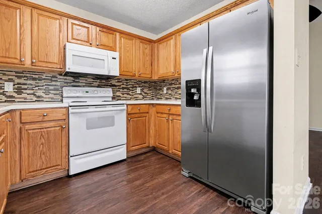 a kitchen with stainless steel appliances granite countertop a refrigerator a sink and white cabinets with wooden floor