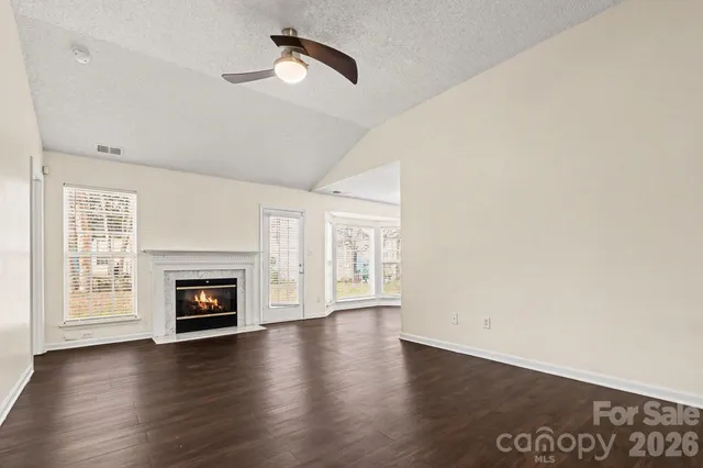 a view of an empty room with window fireplace and wooden floor
