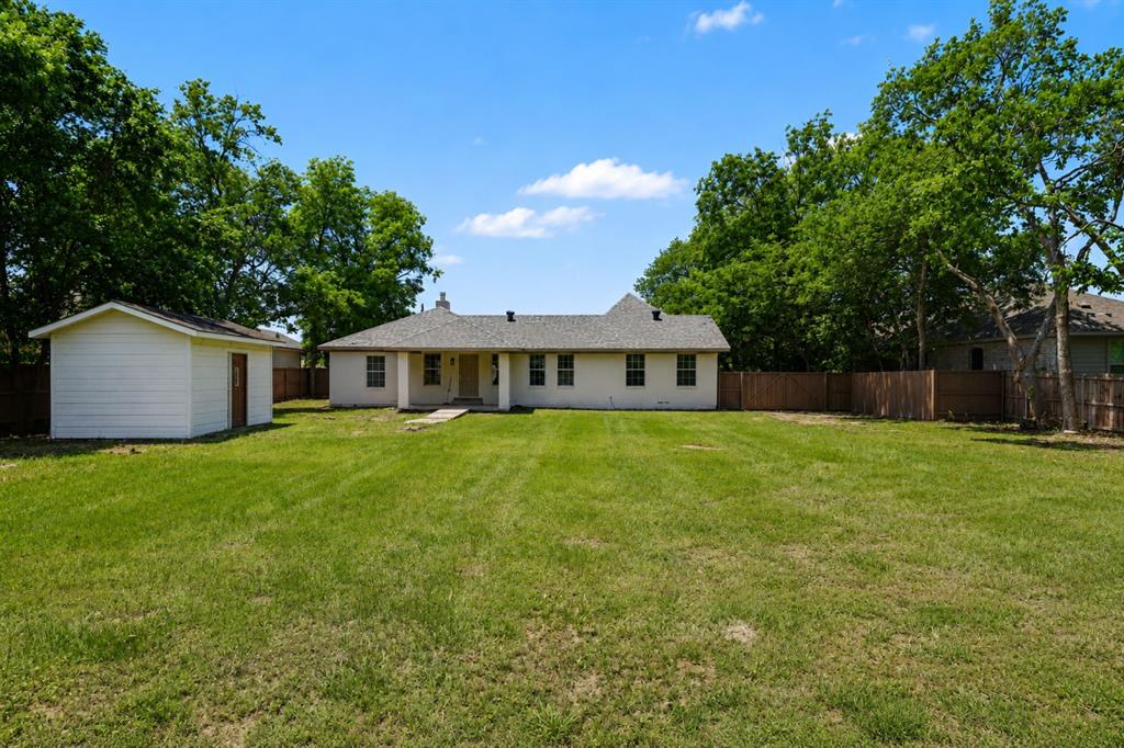 307 Dixon Street Terrell, TX 75160 - Photo 29 of 32 Expansive rear yard featuring a manicured lawn, established perimeter trees, and a wood privacy fence
