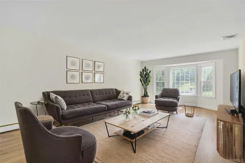 a living room with furniture a flat screen tv and a window