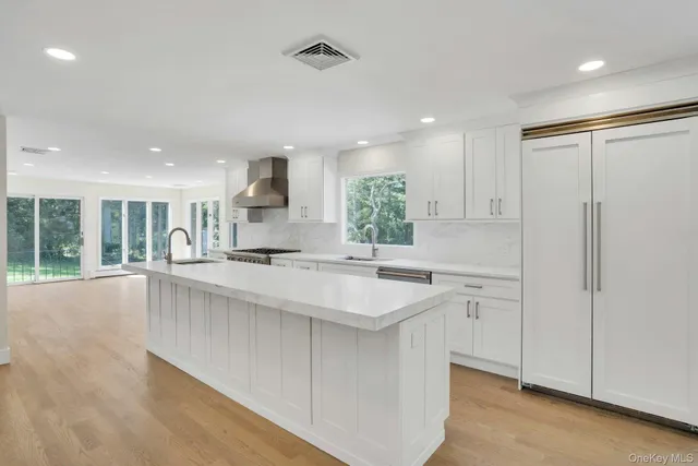 a large white kitchen with a sink window and cabinets
