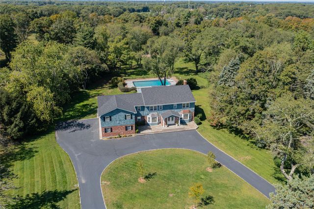 an aerial view of a house with swimming pool and trees