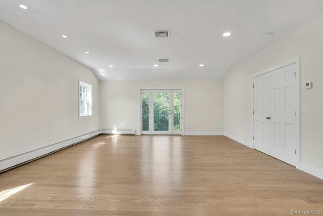 a view of an empty room with wooden floor and window