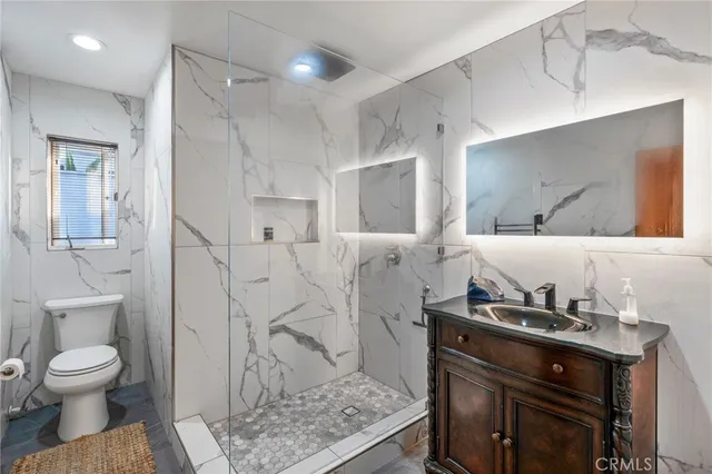 a bathroom with a granite countertop sink a toilet and a mirror