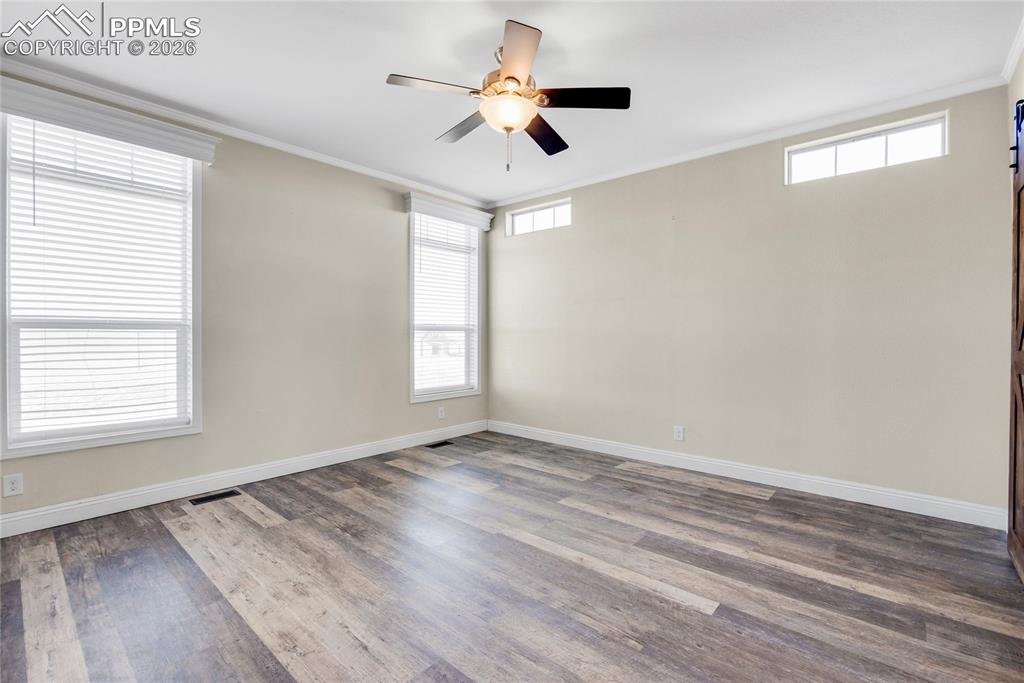 7880 J D Johnson Road Peyton, CO 80831 - Photo 17 of 50 Empty room with ornamental molding, dark wood-type flooring, plenty of natural light, and a ceiling fan