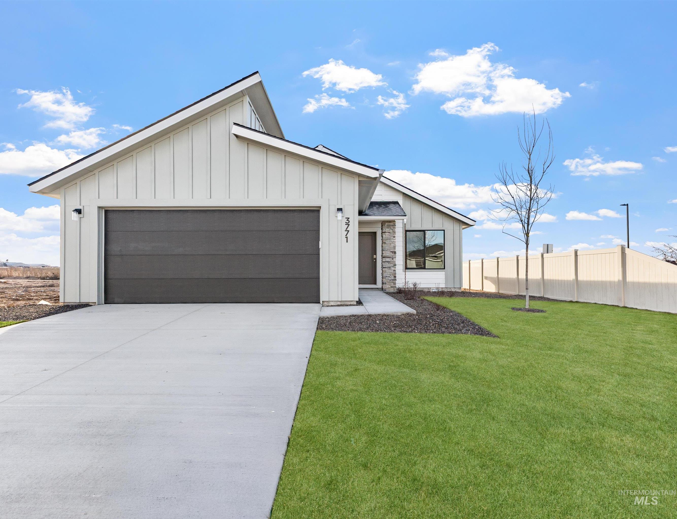 Modern farmhouse featuring board and batten siding, a garage, and driveway