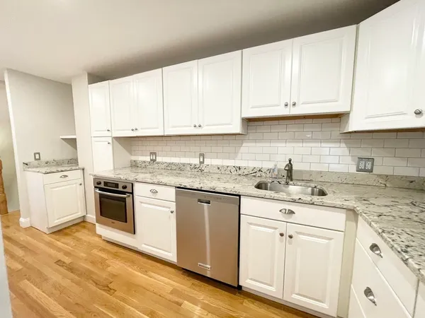 a kitchen with granite countertop white cabinets and white appliances