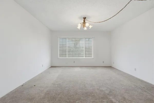 an empty room with windows chandelier fan and windows