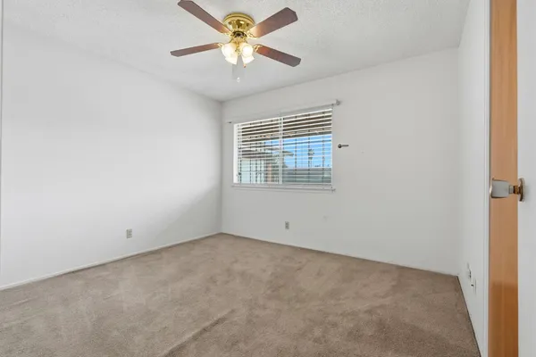 an empty room with a window and a fan