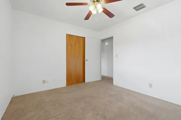 an empty room with a chandelier fan and a ceiling fan