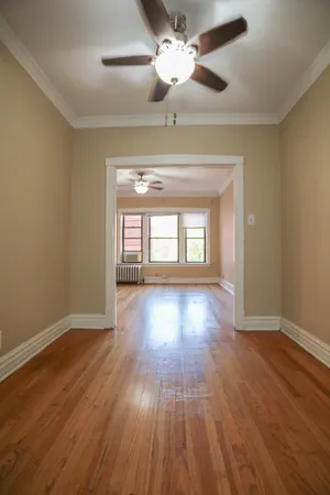 a view of empty room with wooden floor and fan