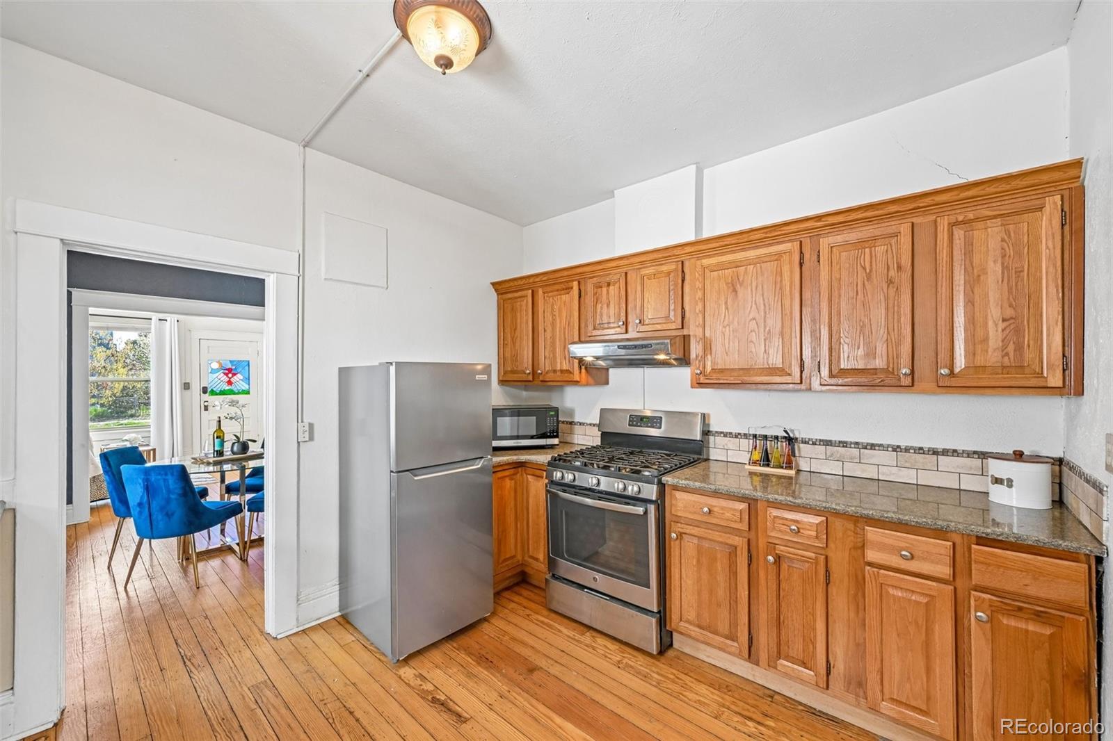 3275 Perry Street Denver, CO 80212 - Photo 10 of 38 a kitchen with stainless steel appliances granite countertop a refrigerator stove top oven and sink with wooden floors